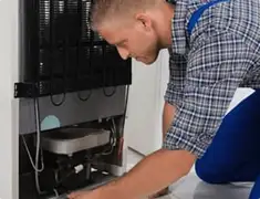 Refrigerator repair technician servicing the compressor and condenser area in Evansville, IN