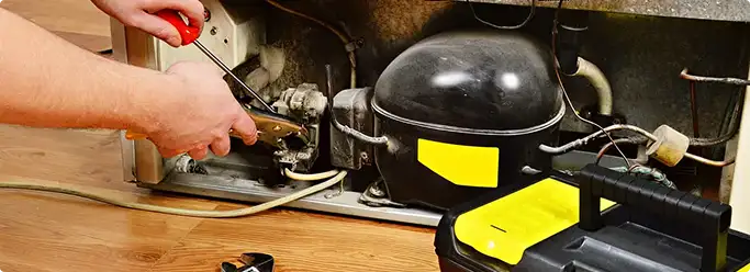 Refrigerator repair technician fixing the compressor and wiring in Evansville, IN