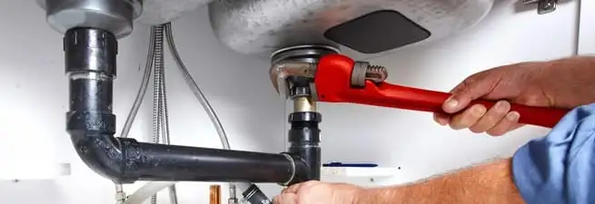 Garbage disposal repair technician tightening the sink drain and disposal connection in Evansville, IN