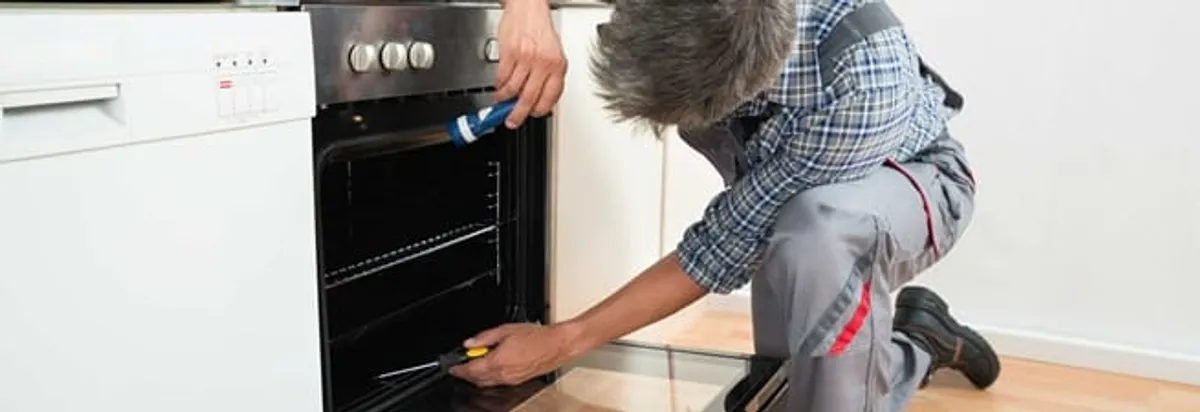 Oven repair technician inspecting and servicing an electric oven in Evansville, IN