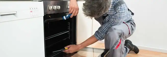 Oven repair technician inspecting and servicing an electric oven in Evansville, IN