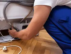 Appliance repair technician fixing refrigerator water line and connections in Evansville, IN