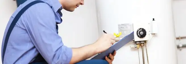 Water heater repair technician inspecting the unit and recording service notes in Evansville, IN